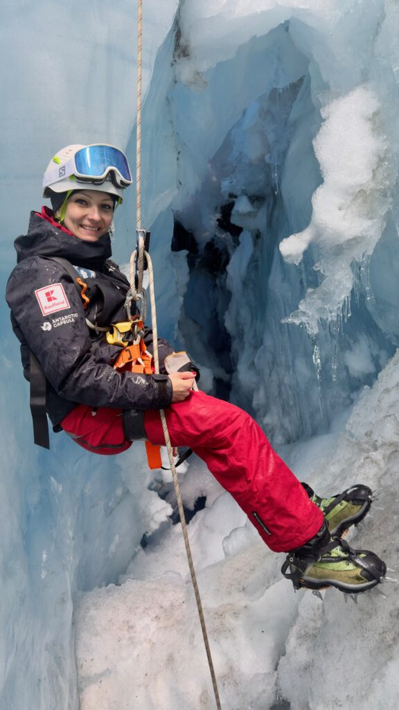 Kremena is sitting back on a rope in front of an icy wall.
