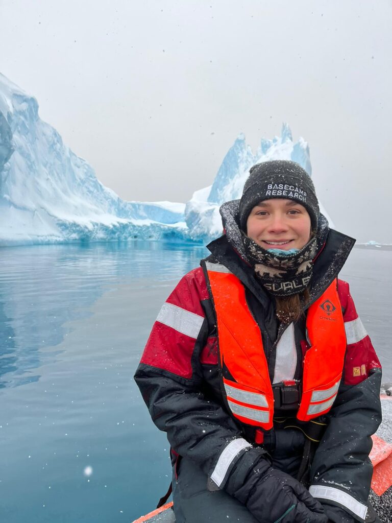 Aurelia is in polar gear and life vest in front of icebergs.